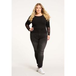 Sort plussize top med blondeærmer og matchende sorte jeans, perfekt til hverdagsbrug, vist med hvide sneakers.