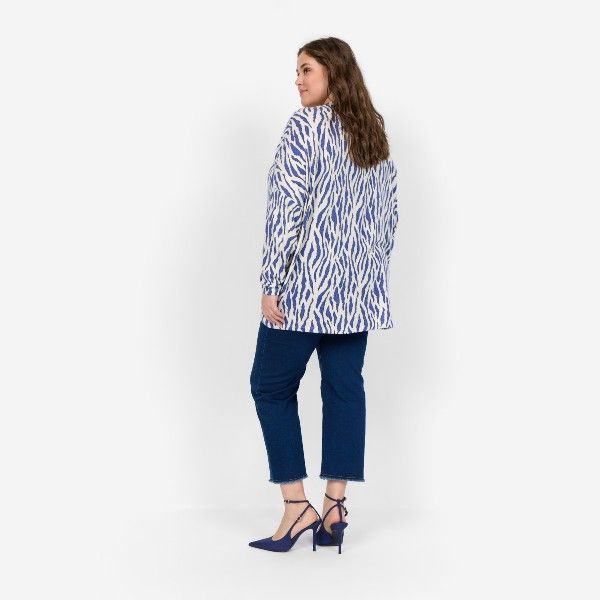 Plussize mode til kvinder: Model i blå og hvid zebrastribet bluse med matchende blå ankellange jeans og højhælede sko. Moderne og komfortabel.