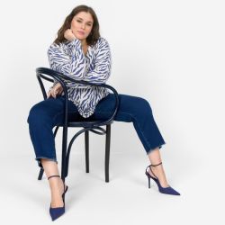 Elegant plussize outfit præsenteret med mørkeblå jeans og matchende stiletter, komplementeret af en zebra-stribet skjorte.