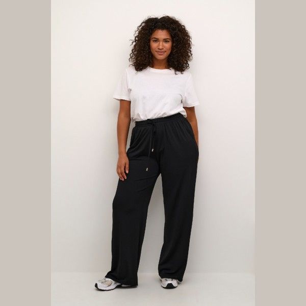 Sorte plussize bukser med høj talje og løs pasform, kombineret med hvid basis-T-shirt og afslappede sneakers. Moderne og komfortabel stil.