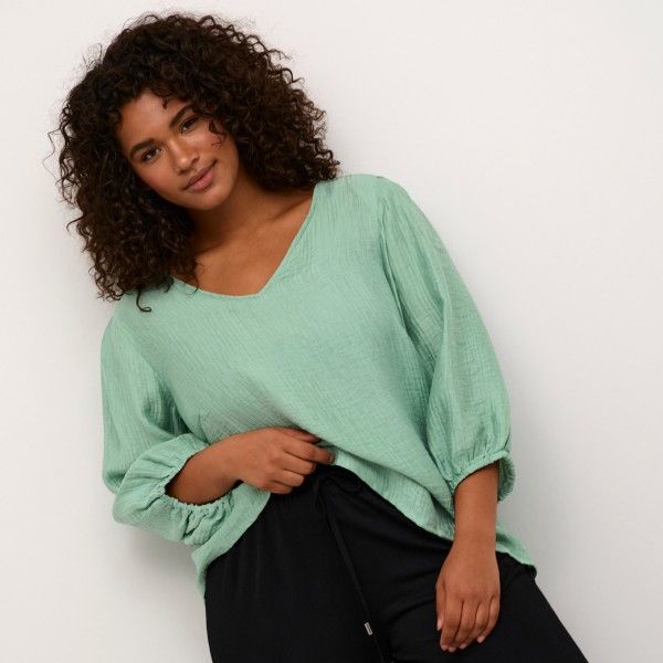 Trendy mintgrøn bluse med trekvart ærmer og elastikdetaljer, kombineret med sorte casual bukser. Perfekt til plus size hverdagsstil.