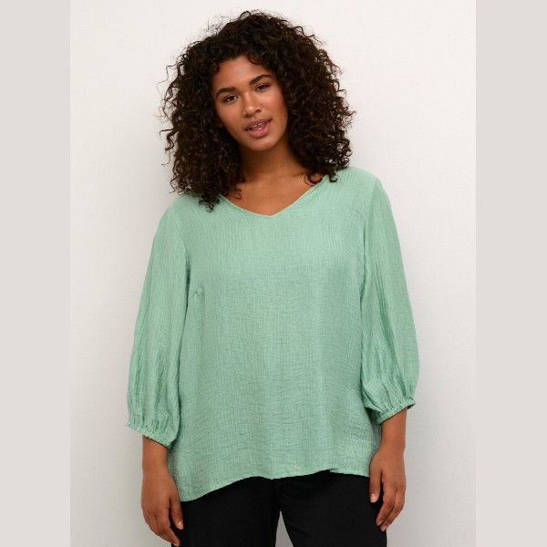 Lys grøn plussize bluse i let materiale med V-hals og 3/4-ærmer, ideel til casual og smart hverdagstøj.