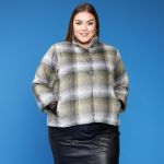 Ternet plussize jakke i grålige nuancer med knapper, kombineret med en sort læder-look nederdel.