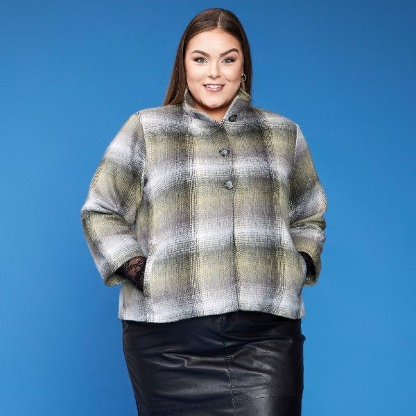 Ternet plussize jakke i grålige nuancer med knapper, kombineret med en sort læder-look nederdel.