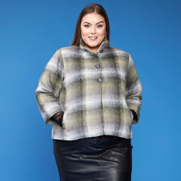 Ternet plussize jakke i grålige nuancer med knapper, kombineret med en sort læder-look nederdel.