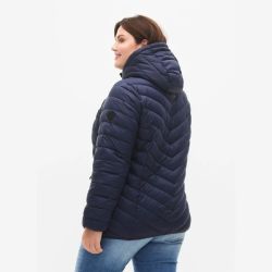 Marineblå quiltet jakke med hætte i plussize, set fra siden, båret over blå jeans.