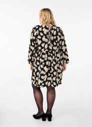 Blomstret plussize kjole med lange ærmer og bånddetalje bagpå, kombineret med sorte strømpebukser og hæle.