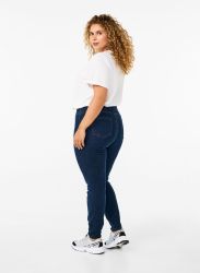 Plussize blå jeans og hvid t-shirt vises på model, der står med sidelæns profil på hvid baggrund.