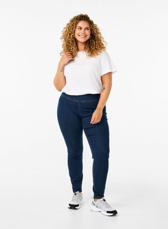 Moderne plussize outfit med mørkeblå skinny jeans og afslappet hvid t-shirt, stylet med sportssko - perfekt til hverdagsbrug.