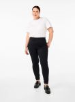 Sort plussize buks og hvid t-shirt står på en ensfarvet baggrund, repræsenterer smart hverdagsbeklædning.