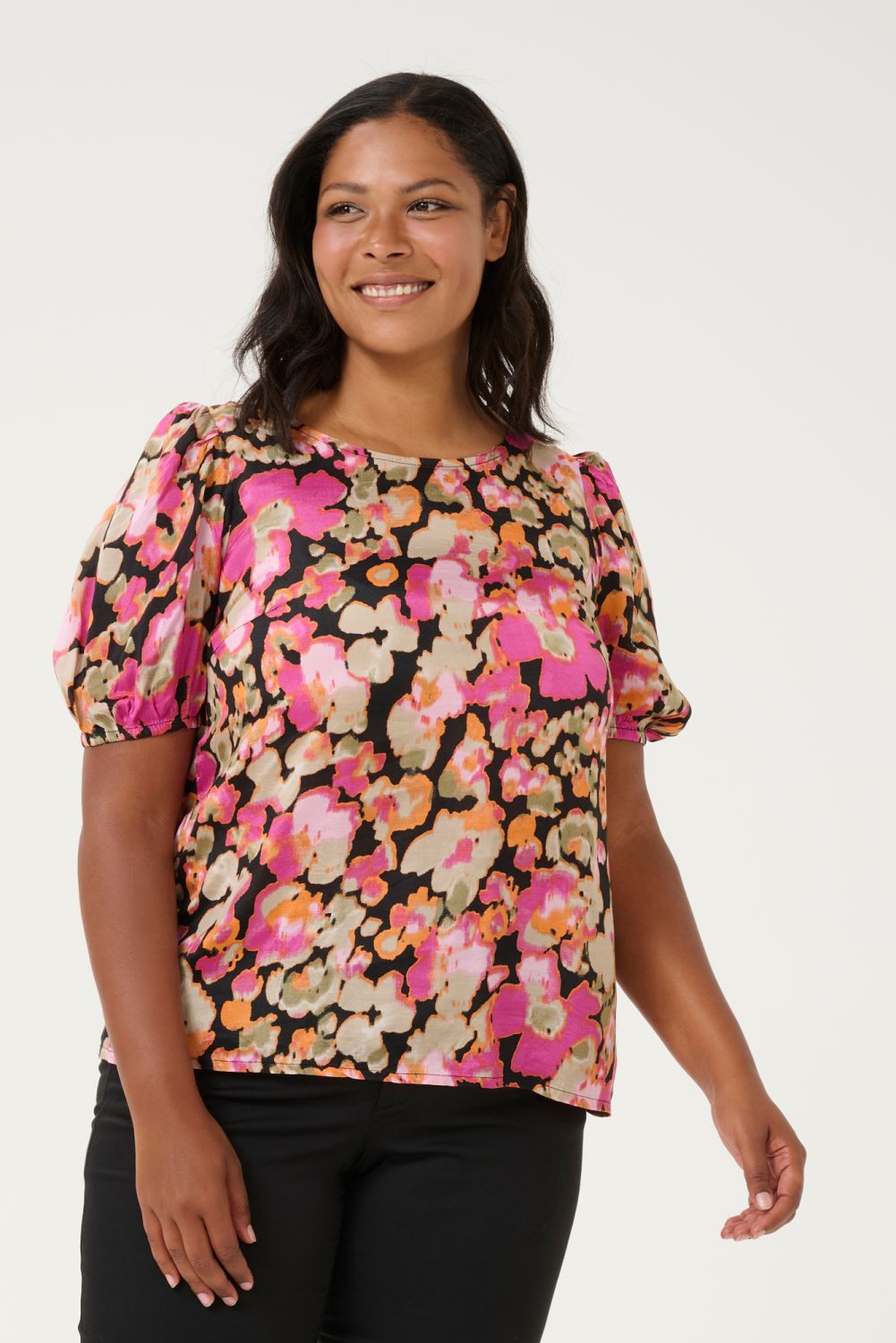 Blomstret plussize bluse i farverige nuancer med korte ærmer og rund hals, præsenteret på lys baggrund.