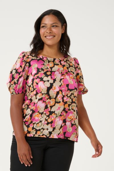 Blomstret plussize bluse i farverige nuancer med korte ærmer og rund hals, præsenteret på lys baggrund.