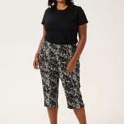 Moderne sort plussize t-shirt med enkle linjer kombineret med mønstrede capri-bukser i sort og hvid. Komplet look til afslappet elegance.