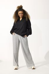 Sort bluse med lange ærmer og gråstribede plussize bukser i fuld længde kombineret med hvide sneakers.