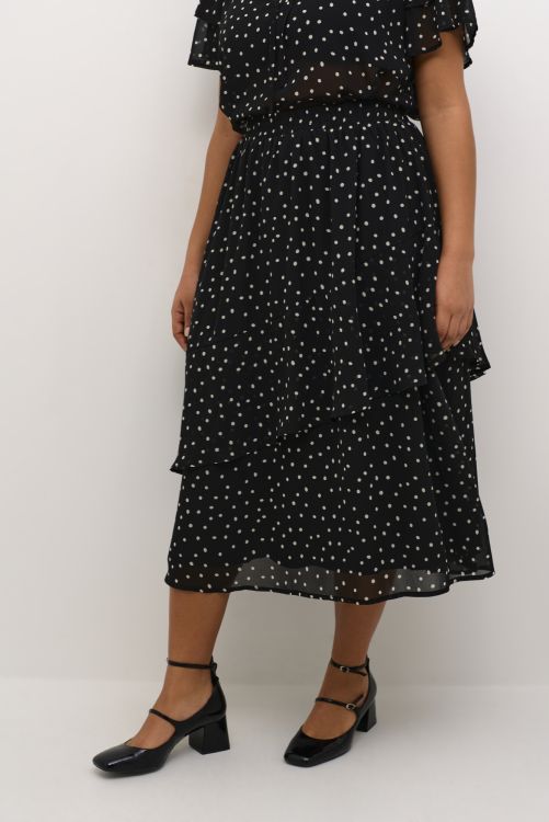 Sort prikket nederdel med flæseærmer og bindebælte, stylet med sorte Mary Jane-sko. Ideal til en stilet hverdag eller særlige begivenheder.