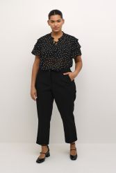 Plussize sort prikket bluse med flæseærmer og snørredetalje samt sorte bukser og højhælede sko for stilfuldt hverdagstøj.
