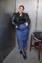 Outfit med plussize-denimnederdel, sort top og læderjakke, akkompagneret af netstrømper og sorte sko.