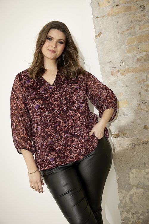 Blomstret plussize bluse og sorte coatede bukser, moderne stil til hverdag eller kontor.