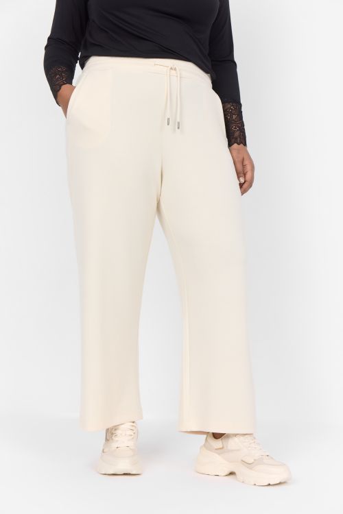 Beige plussize bukser med snøre og lige ben, stylet med sorte detaljer og beige sneakers.