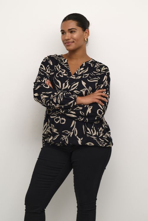 Elegant blomstret bluse med V-udskæring og sorte bukser, der viser et sofistikeret hverdagslook.