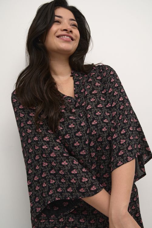 Sort bluse med lyserøde blomsterprint, løs pasform og korte ærmer, velegnet til både hverdags- og arbejdstøj i plussize.