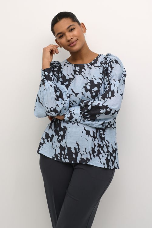 Bluse med blå og sort mønster og lange ærmer kombineret med sorte bukser, egnet til hverdagsbrug og kontor.