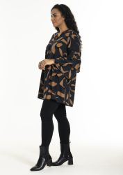 Mønstret plussize tunika med lange ærmer, kombineret med sorte leggings og ankelstøvler.