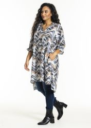 Modetøj til plussize: Geometrisk printet tunika over skinny jeans, akkompagneret af sorte ankelstøvler. Perfect til efterårsstil.