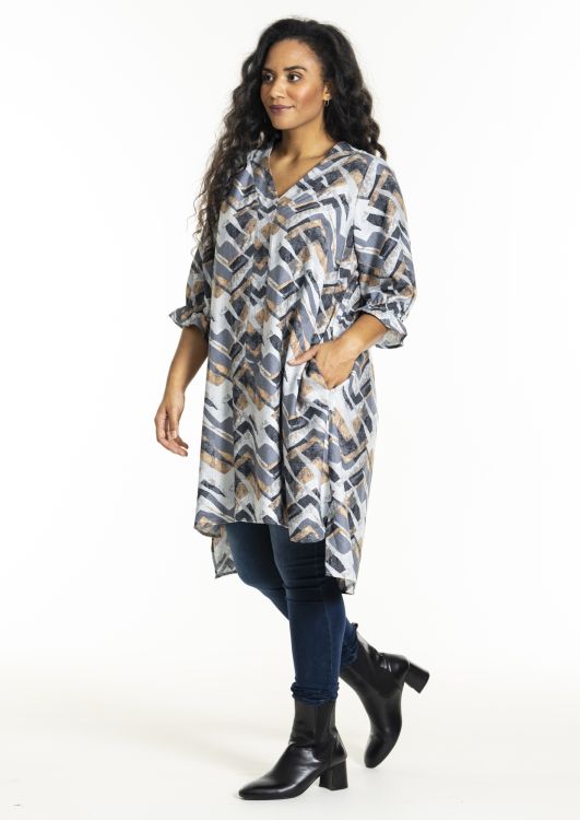 Modetøj til plussize: Geometrisk printet tunika over skinny jeans, akkompagneret af sorte ankelstøvler. Perfect til efterårsstil.