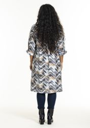 Trendy plussize tunika med geometrisk mønster og 3/4 ærmer, kombineret med mørkeblå skinny jeans og sorte ankelstøvler.