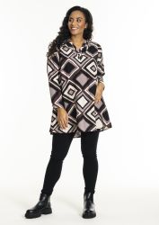 Mønstret tunika i plussize med sort geometrisk design, parret med sorte legging og sorte støvler.