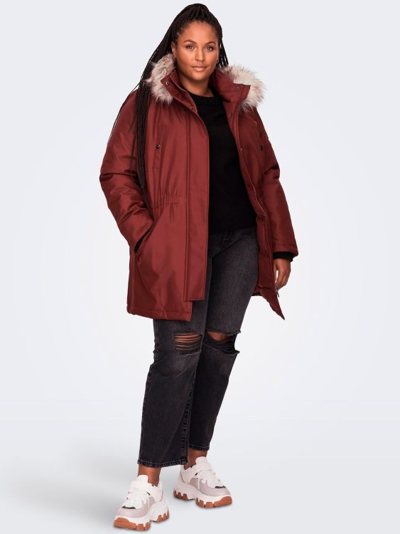 Plussize rød vinterjakke med pelskrave, præsenteret med sort strik og revne mørke jeans, suppleret med hvide sneakers.