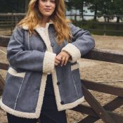 Plussize jakke i grå med hvid foring og fordybning, knaplukning, stående ved træværk, casual efterårsbeklædning.