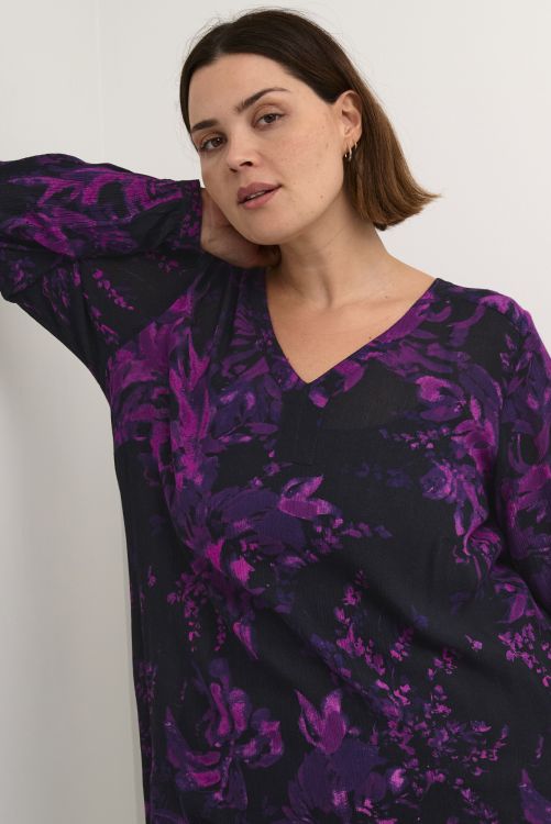 Blomstret plussize tunika i sort og lilla nuancer med V-udskæring og lange ærmer, perfekt til både hverdag og fest.