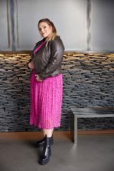 Plussize outfit med pink plissénederdel og brun læderjakke kombineret med sorte ankelstøvler. Stilfuldt hverdagstøj i store størrelser.