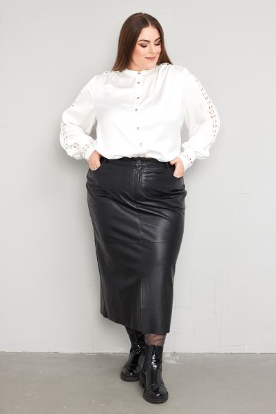 Outfit med hvid bluse med knapper og detaljeret ærmekant, samt sort læderlook nederdel og sorte støvler.