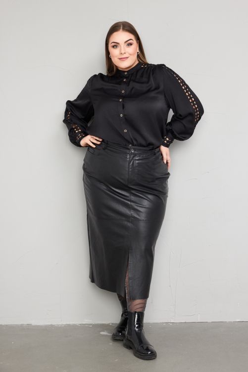 Elegant sort bluse med detaljer på ærmerne og plussize lædernederdel med slids, stylet med sorte støvler.