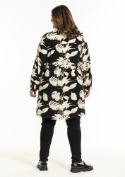 Trendy plussize tøj med blomstermønster og sort baggrund, kombineret med sorte bukser og moderne fodtøj.