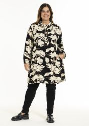 Plussize skjorte-kjole med blomstermønster og sorte leggings imod en hvid baggrund.