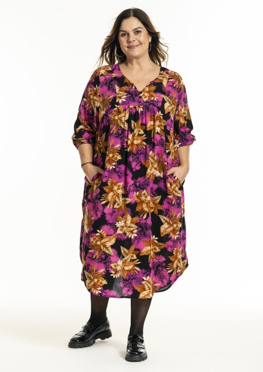 Plussize Gozzip kjole med levende blomsterprint i pink og orange nuancer, lange ærmer og bånd i taljen, perfekt til festlige anledninger.