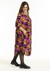 Plussize kjole med blomsterprint i farverne lilla og guld, sammen med sorte strømpebukser og robuste sort sko.