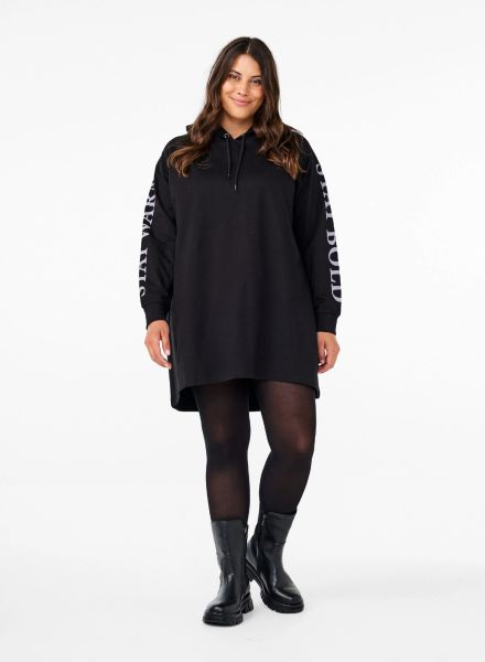 Sort hættetrøje fra Zizzi i plussize med logoprint på ærmerne, kombineret med strømpebukser og læderstøvler.