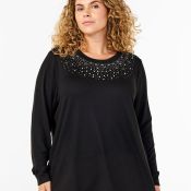 Sort plussize bluse med detaljeret perleudsmykning omkring udskæringen og lange ærmer, præsenteret på neutral baggrund.