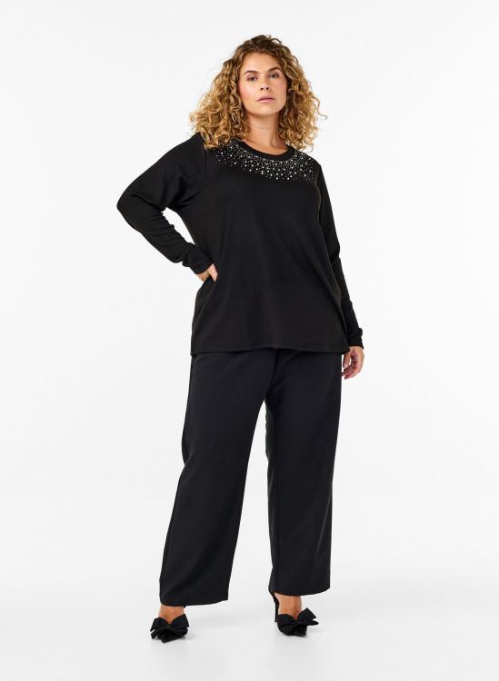 Sort plussize outfit med detaljeret bluse og brede bukser, perfekt til både arbejde og hverdag.