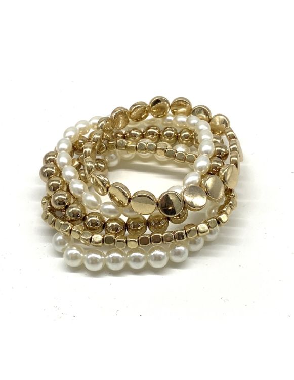 Perlearmbånd og guldtonede elastikarmbånd stablet i elegant mode.