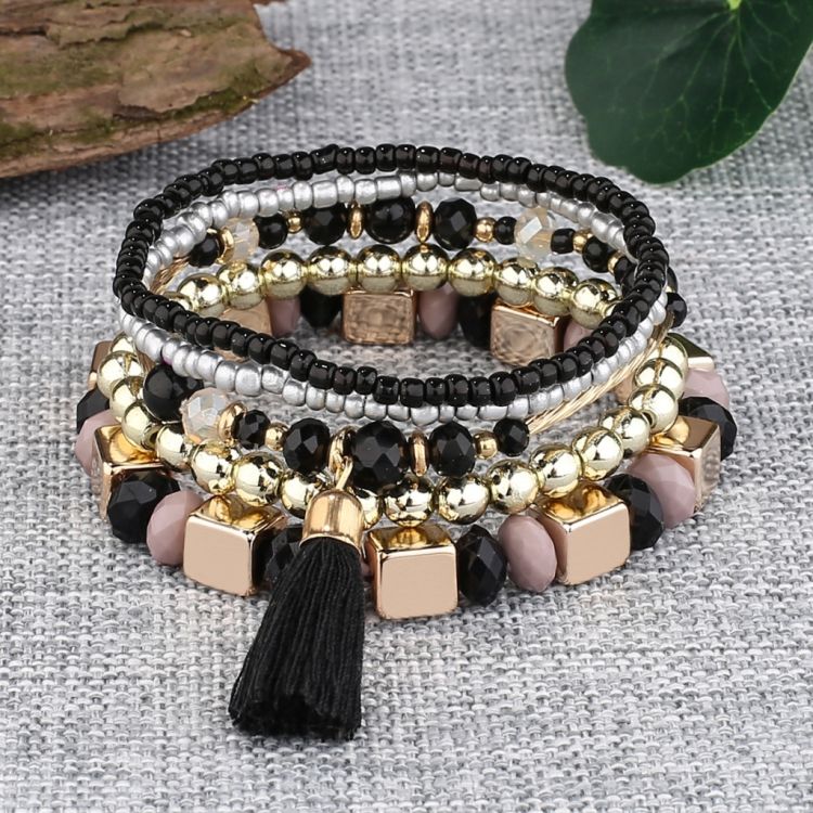 Femlags armbånd med blanding af sorte, sølvfarvede og gyldne perler samt kvast detalje.