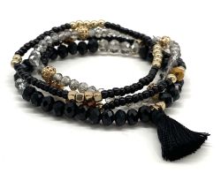 Trendy armbånd med sort kvast, sort og grå facetterede perler samt guld detaljer, perfekt til accessorize.