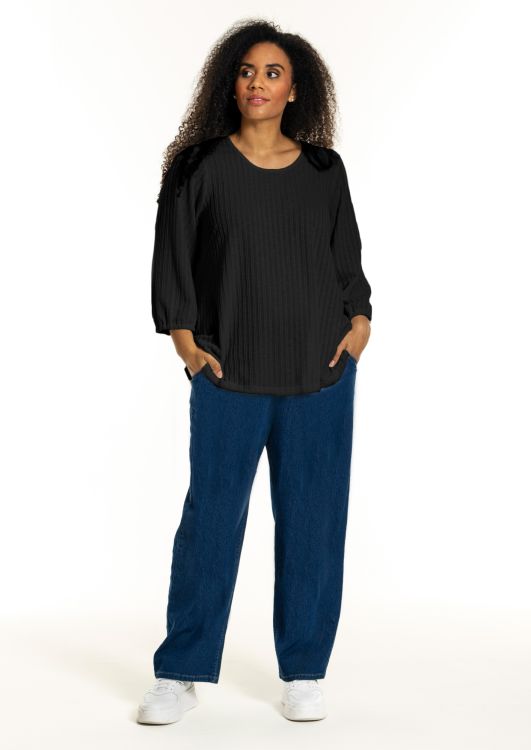 Studio plussize sort bluse med vertikale striber og løse ærmer, sammensat med blå jeans og hvide sneakers.