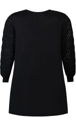 Sort plussize kjole med dekorative mønstre på ærmer, ideel til hverdag og fest, vises mod neutral baggrund.