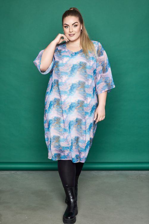 Plussize kjole med skyprint, halvlange ærmer og løs pasform, kombineret med sorte leggings og høje støvler.